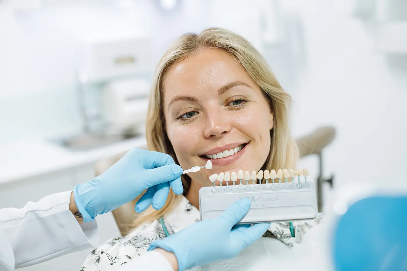 A patient checking her tooth shade against a shade guide